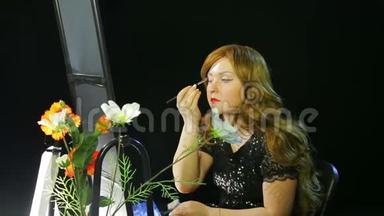化妆室里的红发女演员用蓝色阴影做眼妆，准备上台。